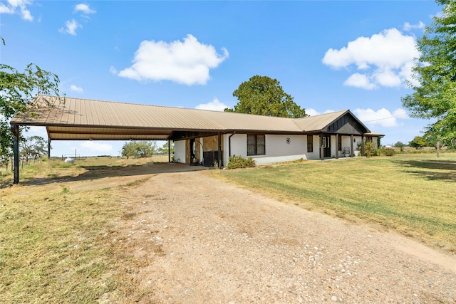 single story home featuring a front lawn, an attached carport, metal roof, and dirt driveway