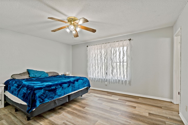 bedroom with light hardwood / wood-style floors, ceiling fan, and a textured ceiling