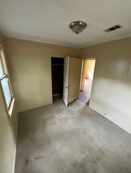 unfurnished bedroom with a closet, ornamental molding, and light tile patterned floors