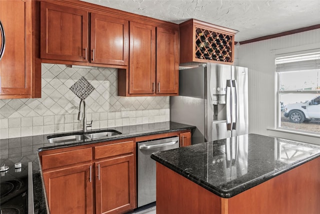 kitchen featuring dark stone counters, a sink, stainless steel appliances, a textured ceiling, and a center island