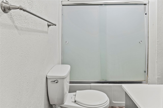 bathroom featuring toilet and a textured wall