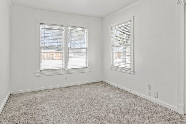 carpeted empty room featuring crown molding and baseboards