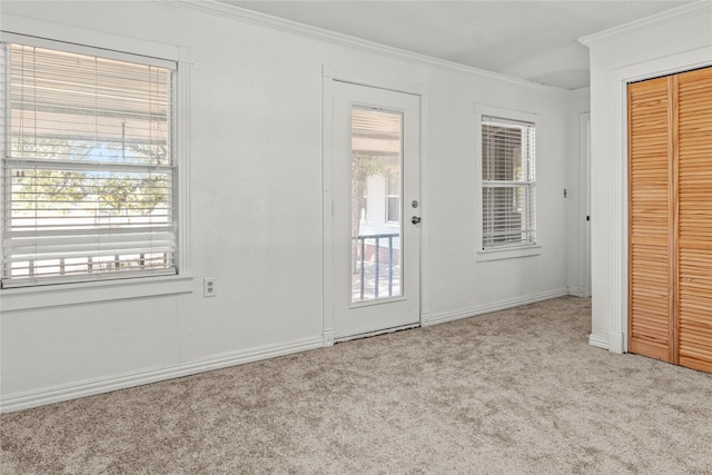 doorway to outside with plenty of natural light, crown molding, baseboards, and carpet floors