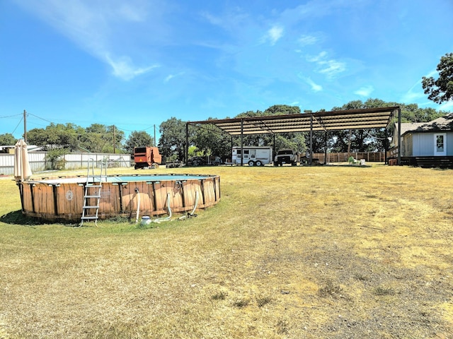 view of yard with a detached carport, fence, and an outdoor pool