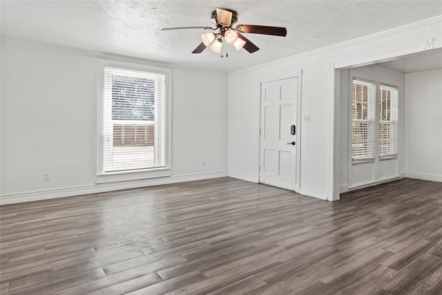 interior space with ornamental molding, a ceiling fan, a textured ceiling, wood finished floors, and baseboards