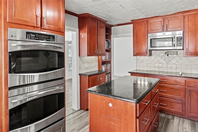 kitchen featuring a kitchen island, light wood-type flooring, dark stone countertops, appliances with stainless steel finishes, and open shelves