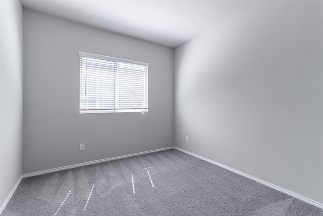 carpeted spare room featuring baseboards