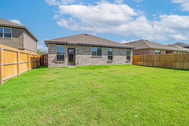 back of house featuring brick siding, a lawn, and a fenced backyard