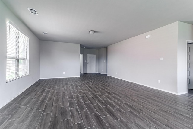 empty room with visible vents, baseboards, and dark wood-type flooring