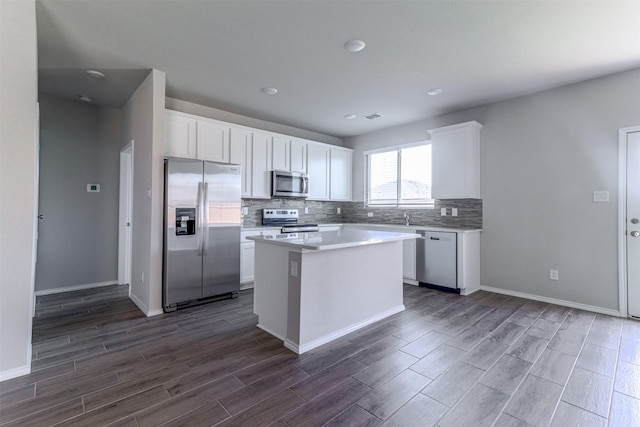 kitchen featuring dark wood-type flooring, a center island, white cabinetry, appliances with stainless steel finishes, and decorative backsplash