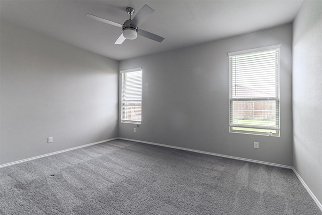 empty room with carpet flooring, a ceiling fan, and baseboards