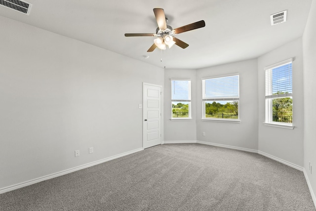 spare room with carpet, baseboards, visible vents, and ceiling fan