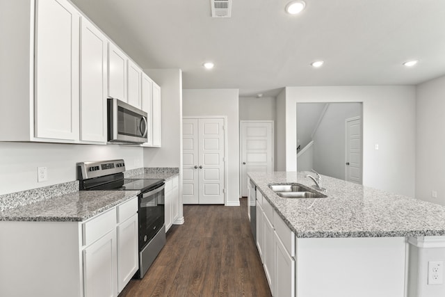 kitchen with dark hardwood / wood-style flooring, an island with sink, white cabinets, appliances with stainless steel finishes, and sink