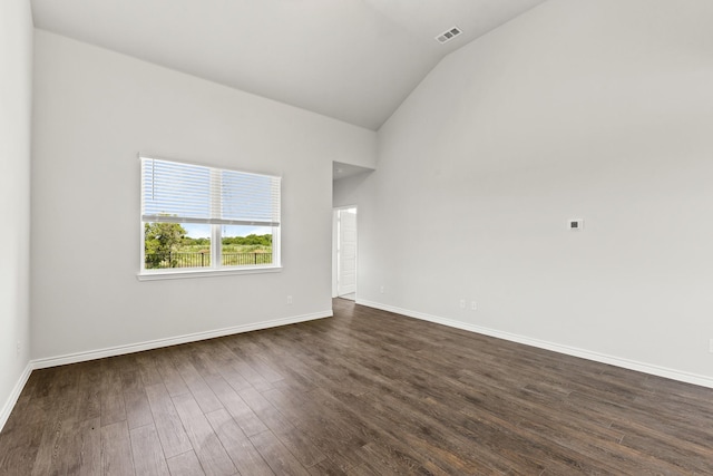 spare room featuring vaulted ceiling, dark wood-style flooring, visible vents, and baseboards