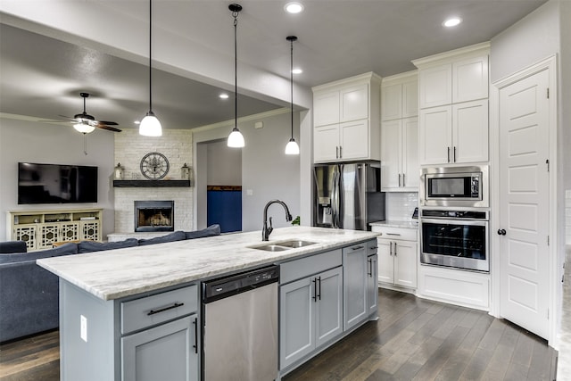 kitchen featuring decorative backsplash, a stone fireplace, sink, crown molding, and stainless steel appliances