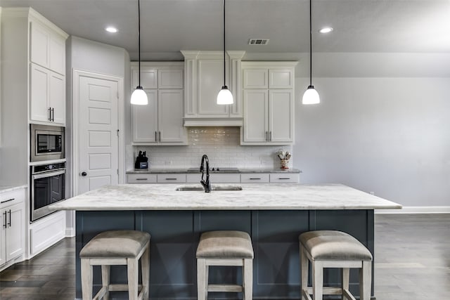 kitchen featuring tasteful backsplash, a center island with sink, appliances with stainless steel finishes, and hardwood / wood-style floors