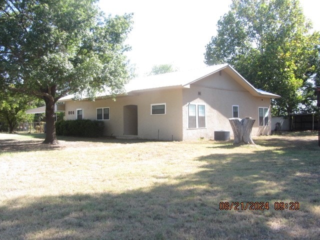 exterior space with central AC unit and a lawn