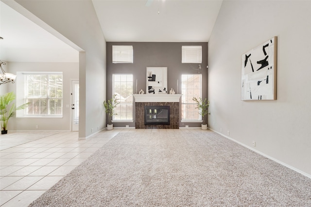 unfurnished living room with high vaulted ceiling, a fireplace, and light colored carpet