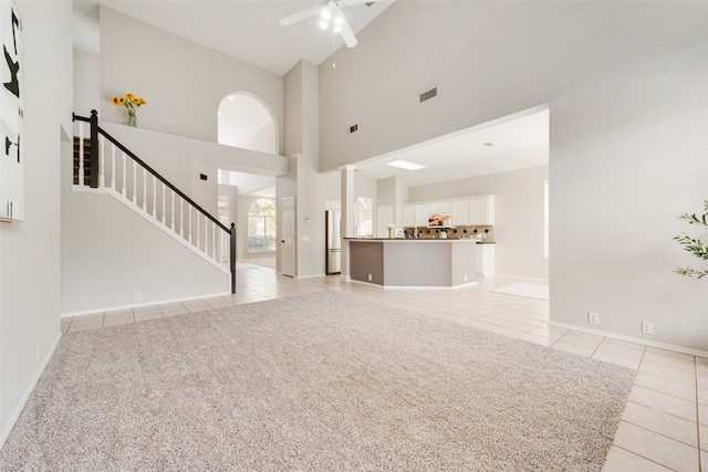 unfurnished living room with ceiling fan, high vaulted ceiling, and light colored carpet