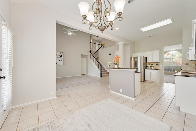 kitchen featuring white cabinetry, stainless steel refrigerator, light tile patterned flooring, and hanging light fixtures