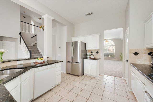 kitchen featuring lofted ceiling, stainless steel fridge, white cabinets, white dishwasher, and dark stone countertops