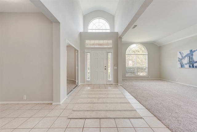 foyer entrance featuring light colored carpet and high vaulted ceiling