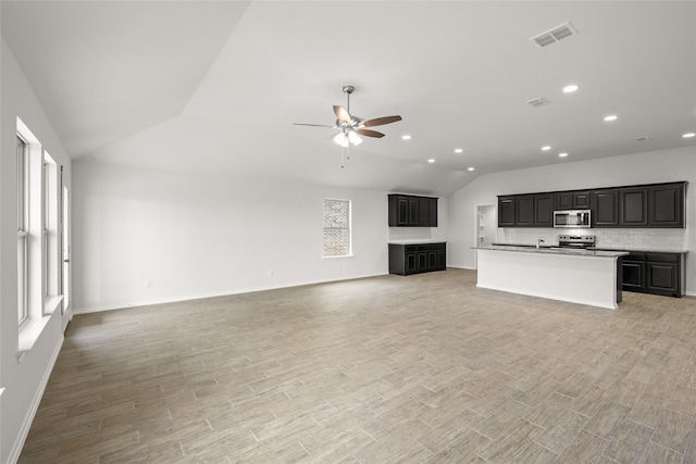 unfurnished living room with vaulted ceiling, ceiling fan, and light wood-type flooring