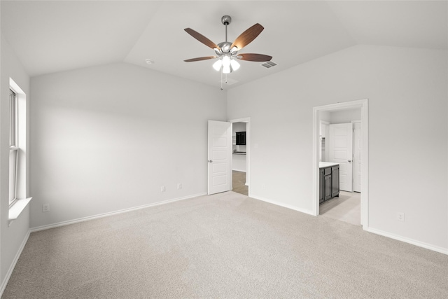 unfurnished bedroom with vaulted ceiling, light carpet, ensuite bathroom, and ceiling fan