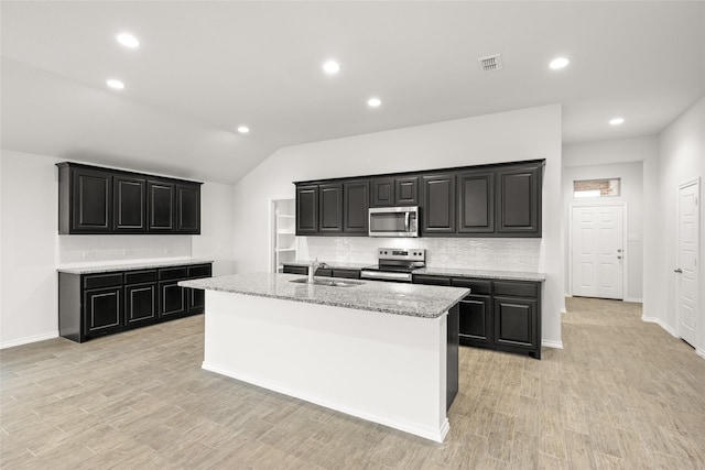 kitchen with stainless steel appliances, a center island with sink, and light hardwood / wood-style floors