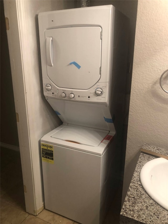 laundry area featuring light tile patterned floors, sink, and stacked washer and dryer