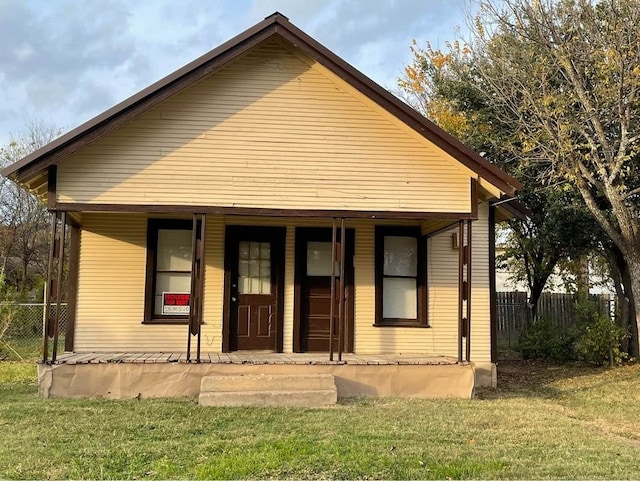 rear view of property featuring a lawn and covered porch