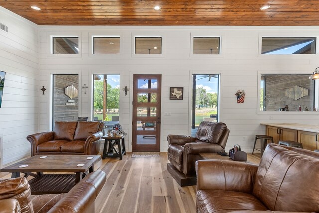 living room featuring wooden ceiling, wood walls, a healthy amount of sunlight, and light hardwood / wood-style flooring