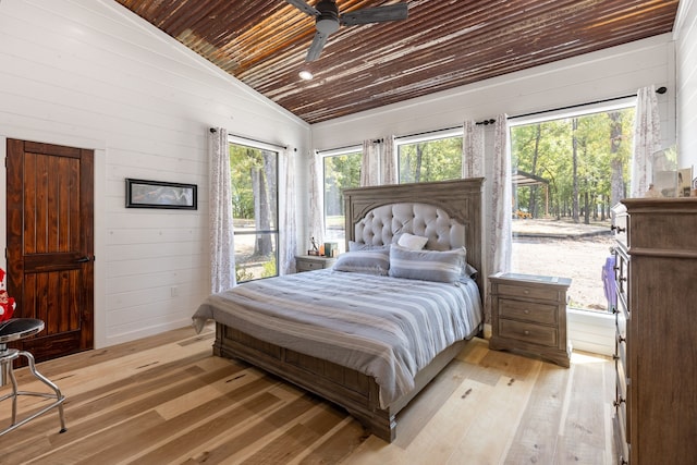 bedroom featuring vaulted ceiling, light wood-type flooring, wood walls, ceiling fan, and wooden ceiling