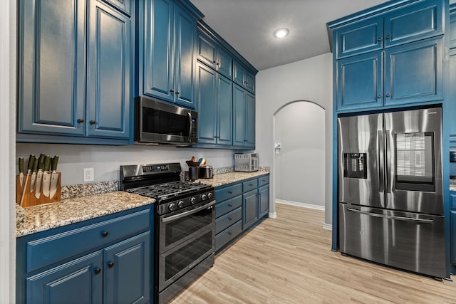 kitchen with light stone countertops, appliances with stainless steel finishes, light hardwood / wood-style flooring, and blue cabinetry