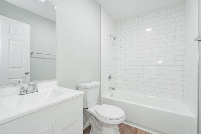 full bathroom with tiled shower / bath, toilet, hardwood / wood-style flooring, and vanity