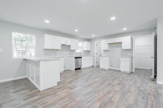 kitchen featuring white cabinets, light hardwood / wood-style floors, kitchen peninsula, and stainless steel dishwasher