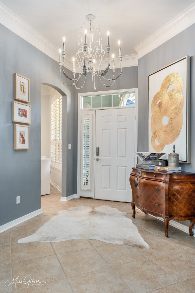 entrance foyer with tile patterned flooring, a notable chandelier, and ornamental molding