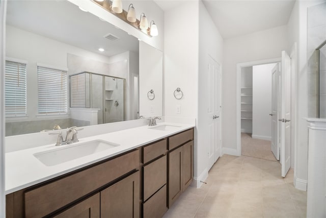 bathroom with a shower with door, vanity, and tile patterned flooring