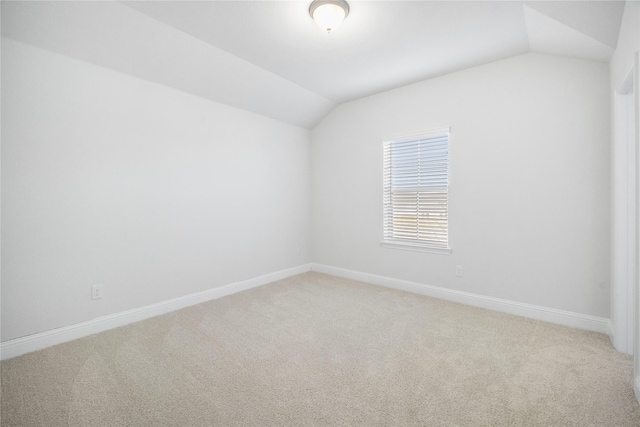 carpeted empty room featuring lofted ceiling