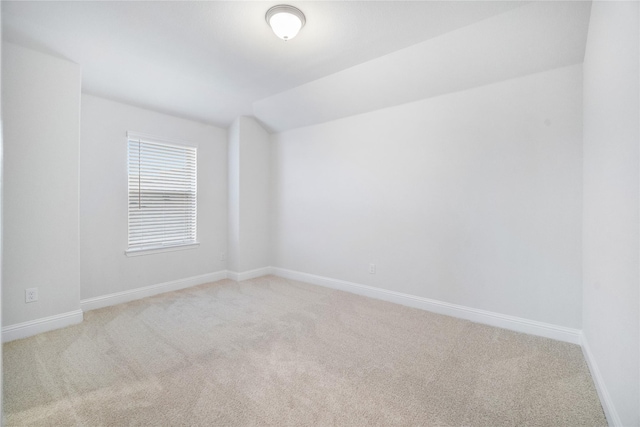 carpeted empty room featuring lofted ceiling