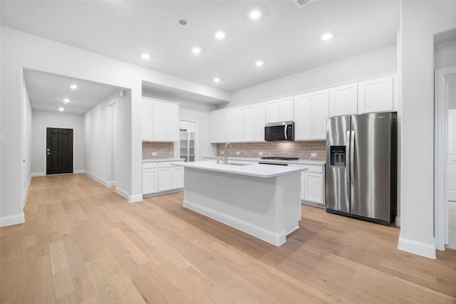 kitchen featuring appliances with stainless steel finishes, a kitchen island with sink, sink, and white cabinets