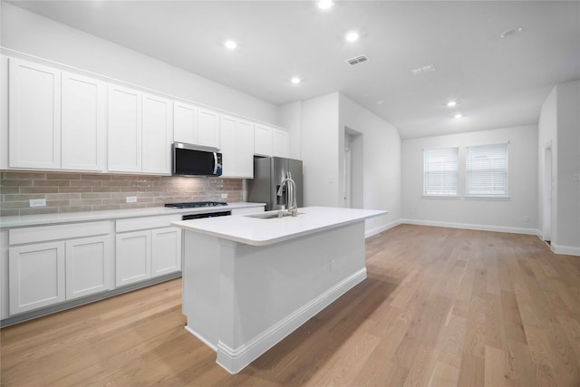 kitchen featuring white cabinetry, sink, stainless steel appliances, and an island with sink