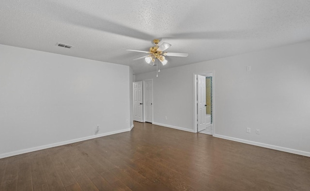empty room with visible vents, a ceiling fan, a textured ceiling, dark wood-style floors, and baseboards