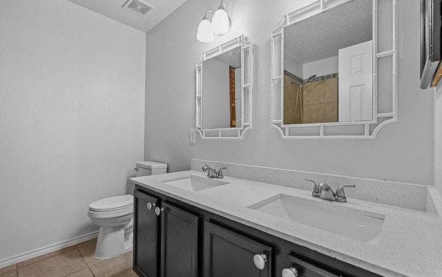 bathroom with tile patterned flooring, toilet, a textured ceiling, and vanity