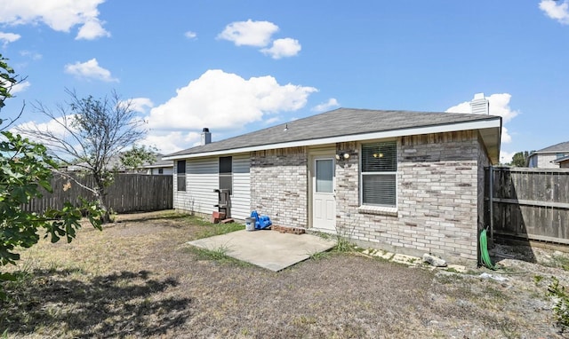 back of property featuring brick siding, a fenced backyard, a chimney, and a patio area