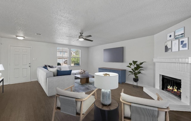 living room featuring visible vents, wood finished floors, a brick fireplace, and ceiling fan