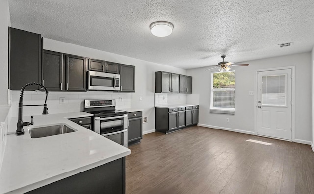 kitchen featuring hardwood / wood-style floors, sink, appliances with stainless steel finishes, a textured ceiling, and ceiling fan