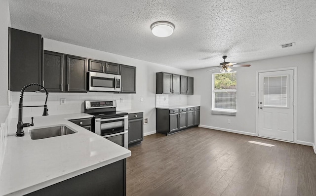 kitchen featuring a ceiling fan, visible vents, dark wood finished floors, a sink, and stainless steel appliances