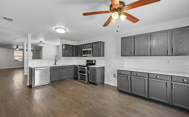kitchen featuring visible vents, dark wood-style floors, stainless steel appliances, a ceiling fan, and a sink