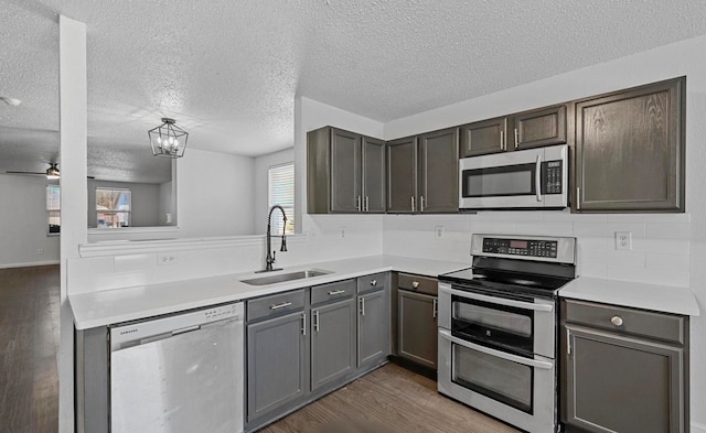 kitchen with sink, stainless steel appliances, dark wood-type flooring, and a textured ceiling